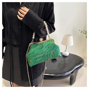 Détail du sac coquillage vert avec poignée en perles et fermoir doré sur fond noir