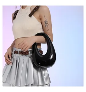 Vista lateral de un bolso negro brillante de charol con una forma de media luna única