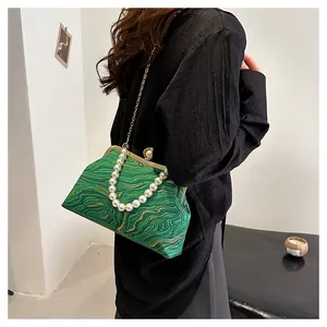 Détail du sac coquillage vert avec texture ondulée, poignée perles et chaîne dorée