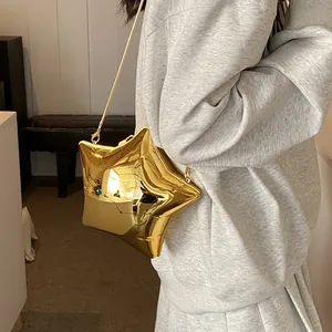 Golden star shaped crossbody bag with metallic chain strap worn by a model