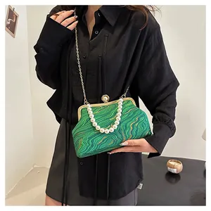 Détail du sac à main vert avec broderie dorée ondulée et grand fermoir à perles chic