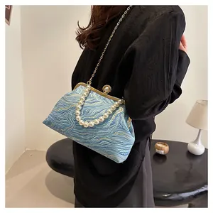 Détail du sac coquillage bleu avec poignée en perles et texture ondulée du tissu