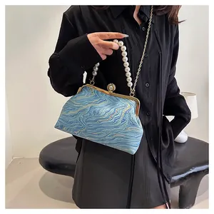 Détail du sac coquille bleu avec motif jacquard vagues et poignée en perles blanches