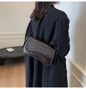 Detail der dunkelbraunen Umhängetasche in Krokostil getragen zu schwarzem Mantel
