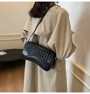 Detailansicht der schwarzen Schultertasche mit Krokoprägung und Goldbeschlägen am Model