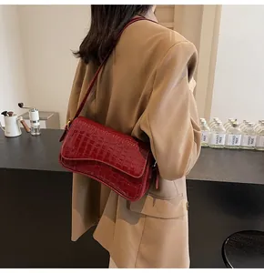 Detail der weinroten Schultertasche mit Krokodilmuster auf einem Khaki-Blazer
