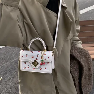 Sac bandoulière blanc à imprimé cerise avec fermoir doré et poignée tressée sur modèle