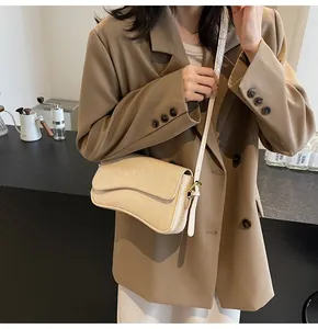 Detail der beigen Handtasche mit Krokoprägung und modernem, halbmondförmigem Boden