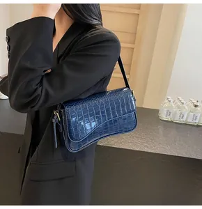 Detailaufnahme der tiefblauen Lackledertasche mit Krokodilmuster an der Schulter