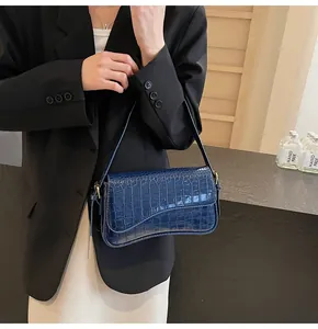 Details der dunkelblauen Baguette-Tasche mit Krokodilmuster, Glanzoptik und Golddekor