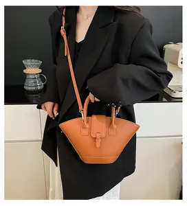 Brown fan-shaped handbag worn as a crossbody bag in a minimalist lifestyle setting