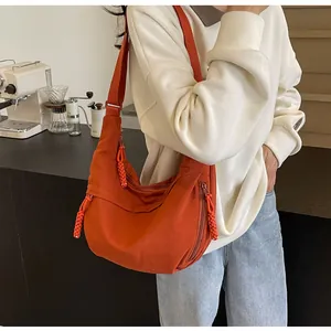 Detail der orangefarbenen Nylon-Umhängetasche in Halbmondform mit drei Reißverschlusstaschen