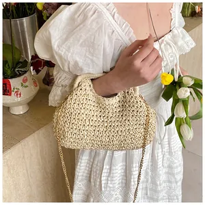 Close-up detail of cream woven beach bag with golden chain and half-moon handle