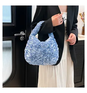 Detailed view of light blue pleated satin handbag with dense wave texture and soft handle