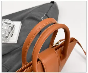 Detail of caramel leather handbag handle with precision stitching and golden metal hardware
