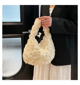 Detail of cream pleated handbag featuring dense ruffled layers and elegant satin texture