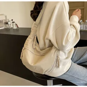 Modell mit cremefarbener Halbmondtasche mit breitem Gurt in einem Café-Ambiente