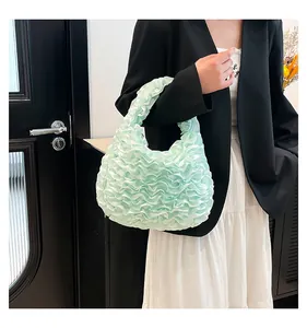 Detail of light green ruffled handbag with pleats held by model in black suit