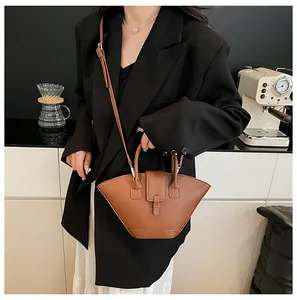 Brown fan-shaped crossbody bag worn with a black blazer in a chic cafe setting