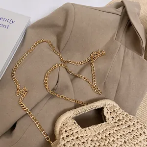 Close-up of golden chain strap on a beige hand-woven straw bag with premium texture