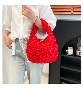 Close-up of vibrant red pleated cloud bag featuring glossy silk texture and handle detail