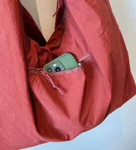 Dettaglio della tasca frontale con zip sulla borsa a tracolla in nylon rosso mattone