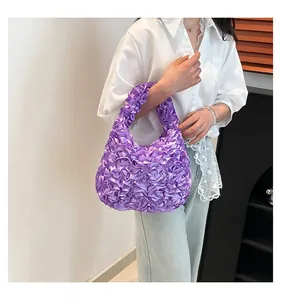 Fashionable purple ruffled satin handbag shown as a stylish shoulder bag on a model