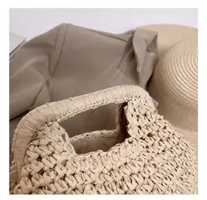 Close-up of beige woven straw beach bag featuring an integrated hollow handle detail