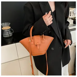 Detail view of caramel fan-shaped leather handbag with sleek top handle and shoulder strap