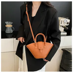 Retro orange-brown fan-shaped handbag worn by a model in a minimalist modern setting