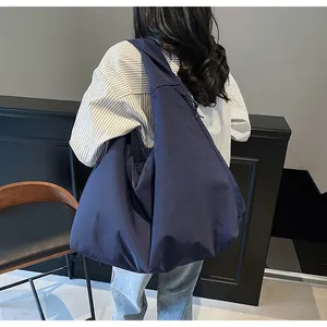 Dettaglio borsa tote in nylon blu scuro con coulisse laterale dallo stile minimalista