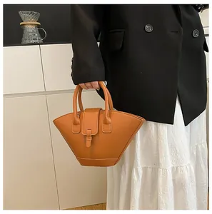 Detail of camel brown fan-shaped handbag featuring premium matte leather texture and clasp