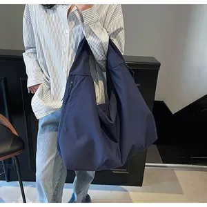 Dettaglio della borsa a spalla in nylon blu scuro con tasca laterale e trama morbida