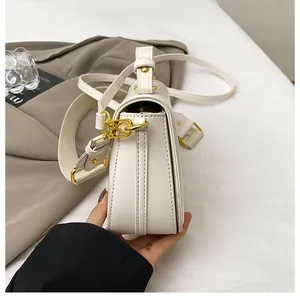 Détail du sac à bandoulière blanc crème avec boucle dorée et texture en similicuir