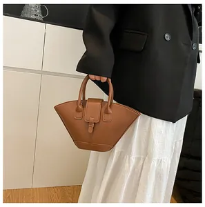 Detail of caramel brown fan-shaped handbag with round handles and matte leather texture