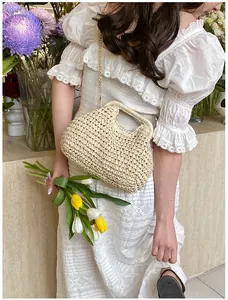Detail of hand-woven straw shell bag with gold chain strap on floral background