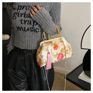 Detail of vintage floral shell bag featuring a natural bamboo handle and long pink tassel