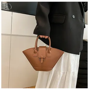 Detail of dark brown leather fan-shaped handbag with elegant buckle and handle