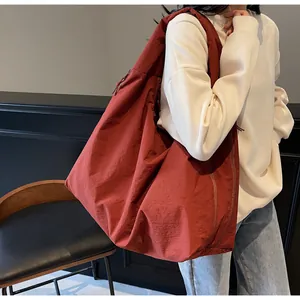 Dettaglio macro della borsa a tracolla in nylon rosso mattone con trama di tessuto a pieghe