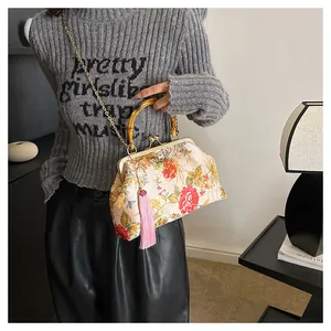 Detail of floral shell bag with bamboo handle, gold chain strap and pink silk tassel