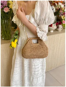 Detail of handmade straw beach bag with gold chain strap on a white lace dress backdrop