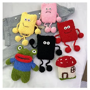 Detailed knit texture of handmade crochet frog and mushroom crossbody bags on denim