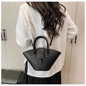 Macro detail of a minimalist black trapezoidal handbag with matte leather texture