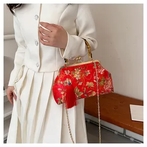 Detail of red floral brocade bag with bamboo handle and elegant silk tassel