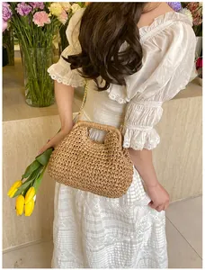 Detail of hand-woven straw shell bag with gold chain strap on a floral dress model