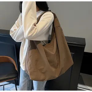 Grande borsa hobo marrone in nylon indossata per mostrare le dimensioni e lo stile casual