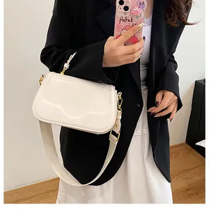 Détail du sac à bandoulière crème avec rabat festonné et large sangle portée par un mannequin