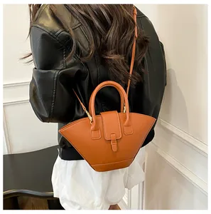 Model wearing a caramel fan-shaped leather crossbody bag with curved top handle