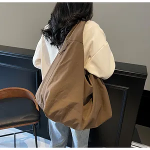 Vista posteriore della modella con una grande borsa a spalla in nylon marrone con zip
