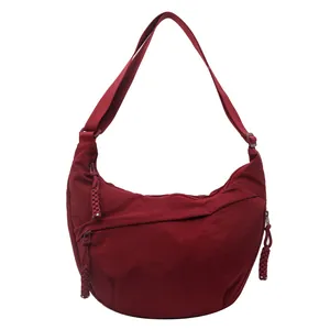 Bolso bandolera de media luna rojo vino con detalles tejidos y cierre de cremallera